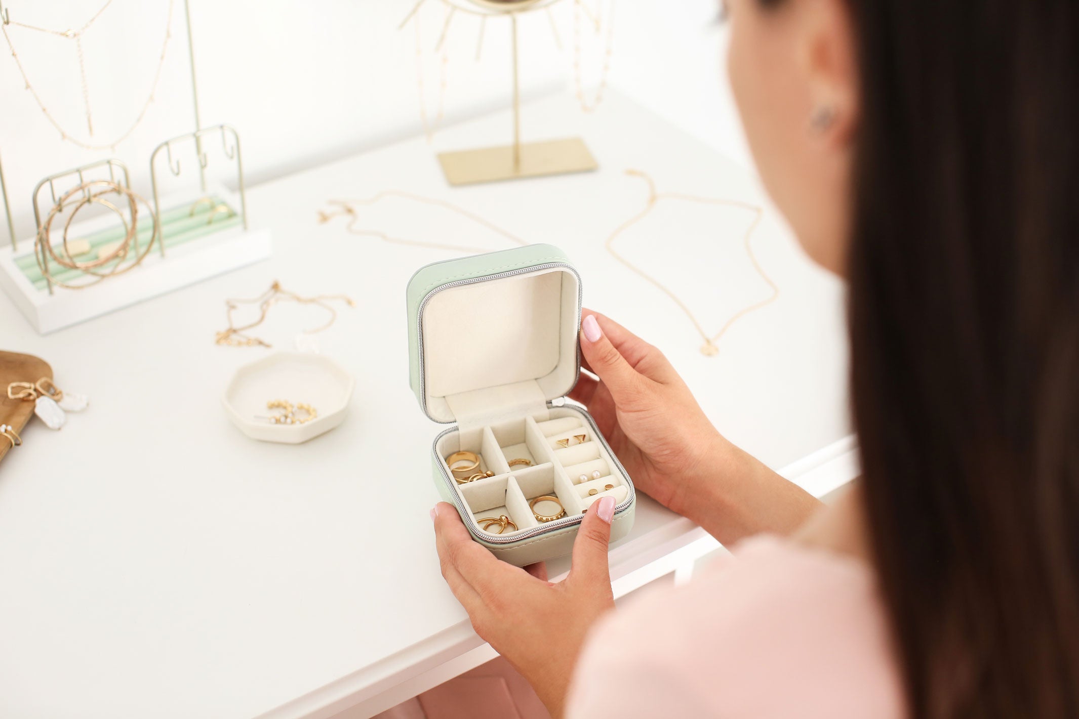 Femme en train de regarder son écrin à bijoux dans lequel se trouve des bijoux cassés.